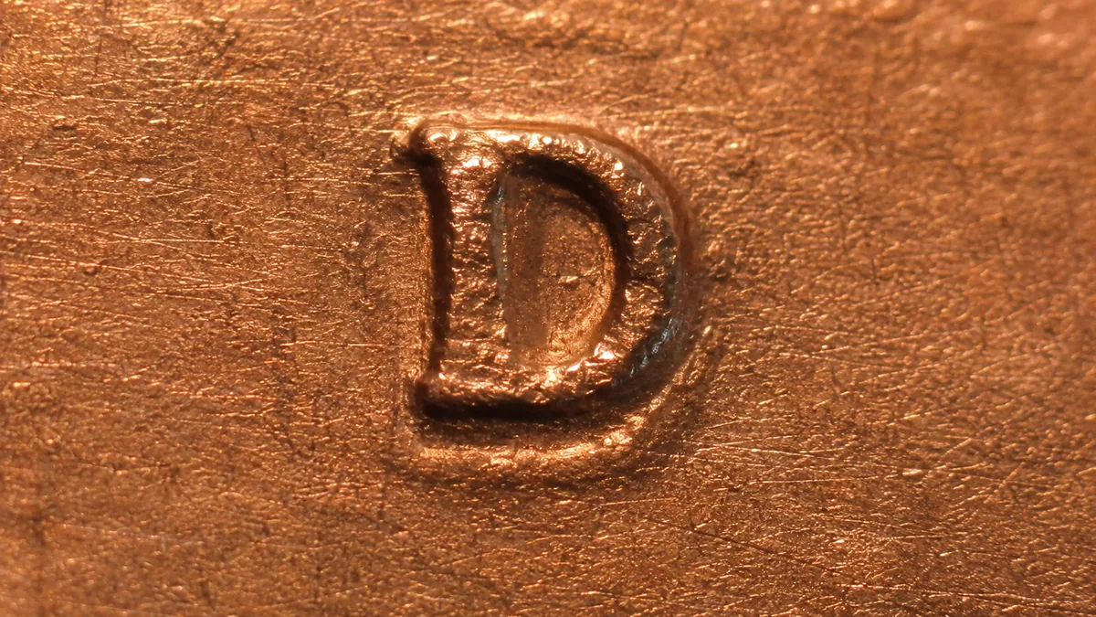 Extreme macro of a raised mintmark letter with a partial second impression beneath it